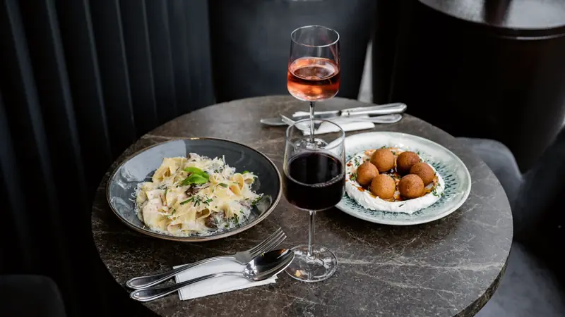 Table de restaurant avec deux assiettes, un verre de vin rouge et un verre de rosé