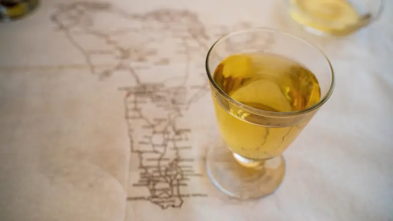 Verre de vin blanc posé sur une nappe imprimée d'une carte ancienne