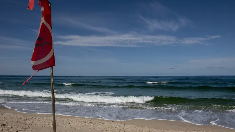 Drapeau rouge planté sur une plage face aux vagues