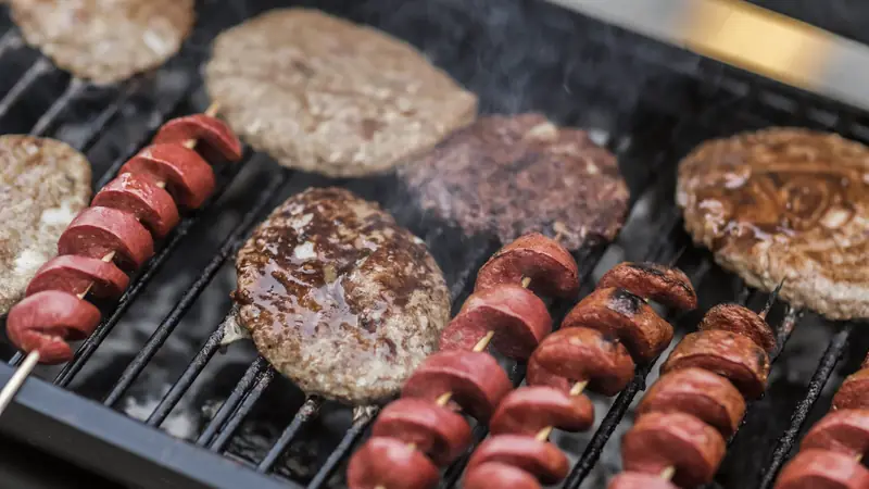Saucisses et steaks hachés grillant sur un barbecue