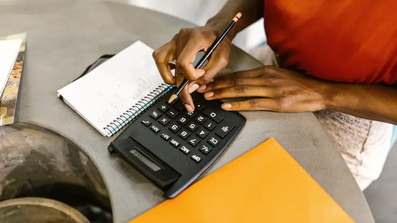 Mains calculant un budget avec une calculatrice et un carnet