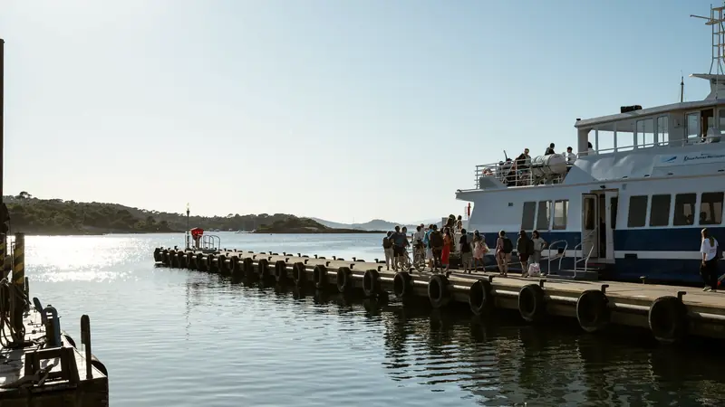 Passagers et cyclistes embarquant sur un bateau de ligne amarré à un ponton par temps ensoleillé