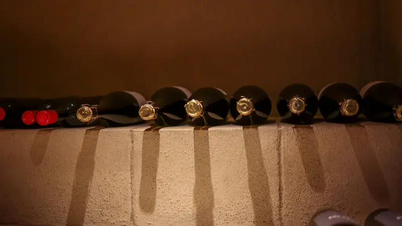 Bouteilles de vin couchées dans des alvéoles de pierre, dans la pénombre d'une cave