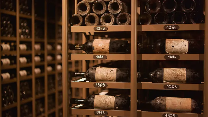 Vieilles bouteilles de vin rouge couchées dans une cave voûtée