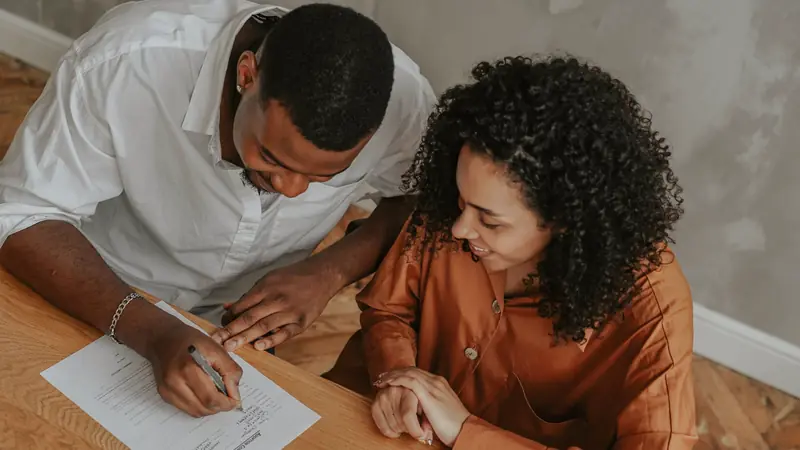 Couple relisant et signant un document à une table