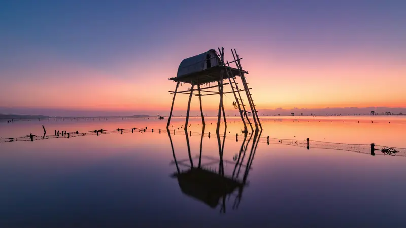 Carrelet, cabane de pêche sur pilotis au bord de l'eau au coucher du soleil