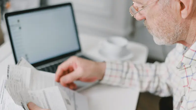 Homme vérifiant des factures devant un ordinateur portable