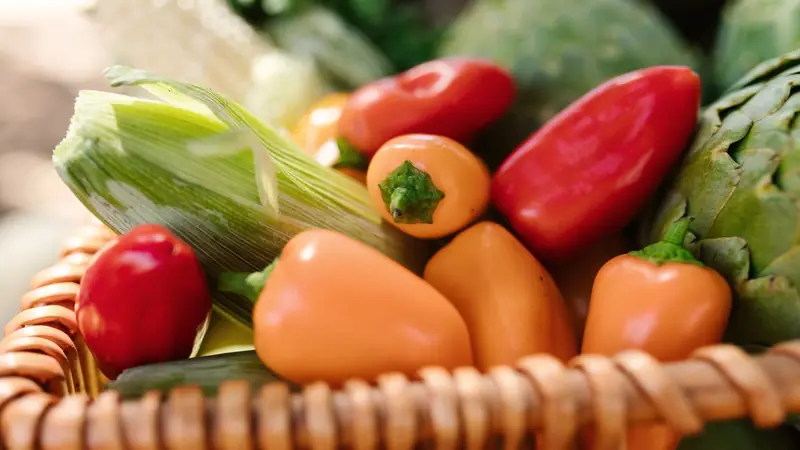 Panier en osier rempli de poivrons, tomates et légumes de saison