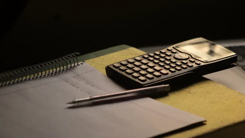 Calculatrice et stylo posés sur un cahier