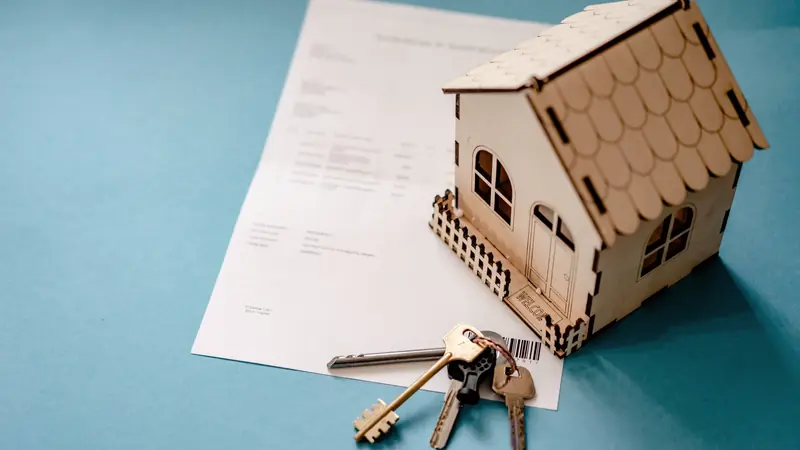 Maquette de maison en bois et trousseau de clés posés sur un document