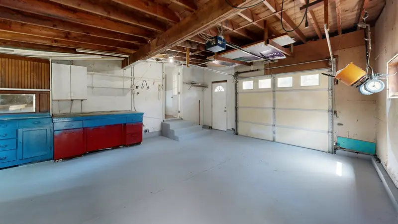 Garage de maison vide avec une porte sectionnelle et un plafond en bois