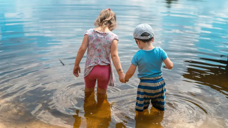 Enfants jouant dans l'eau peu profonde au bord d'un lac