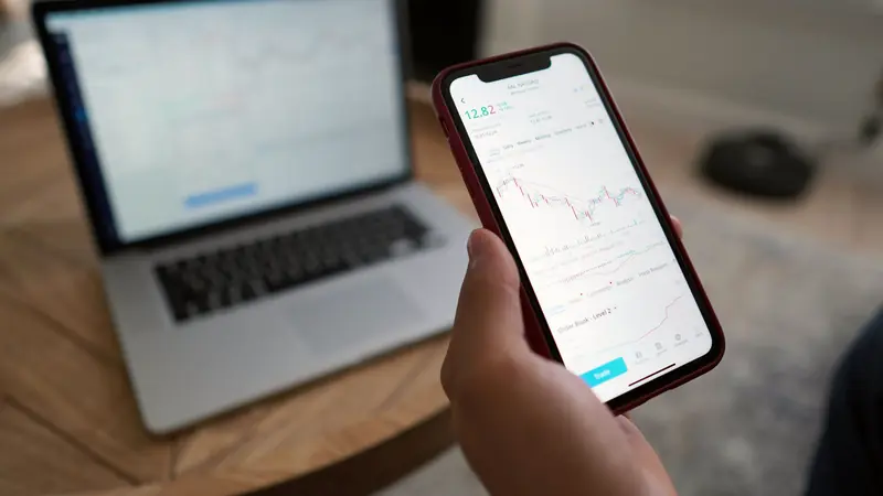 Personne consultant une application sur son téléphone devant un ordinateur portable