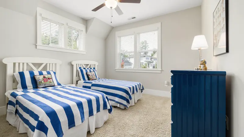 Chambre lumineuse avec deux lits simples aux draps rayés