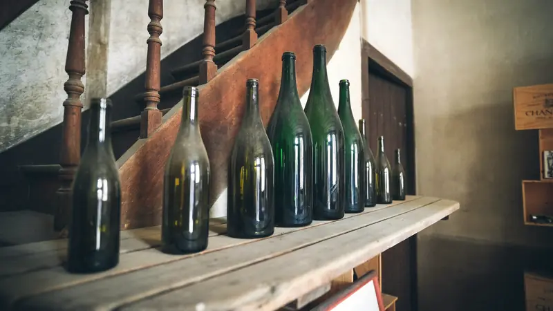 Vieilles bouteilles poussiéreuses alignées sur une étagère en bois