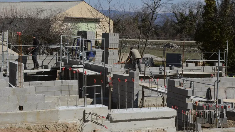 Chantier de maison avec murs en parpaings sur fondations en béton et attentes d'acier