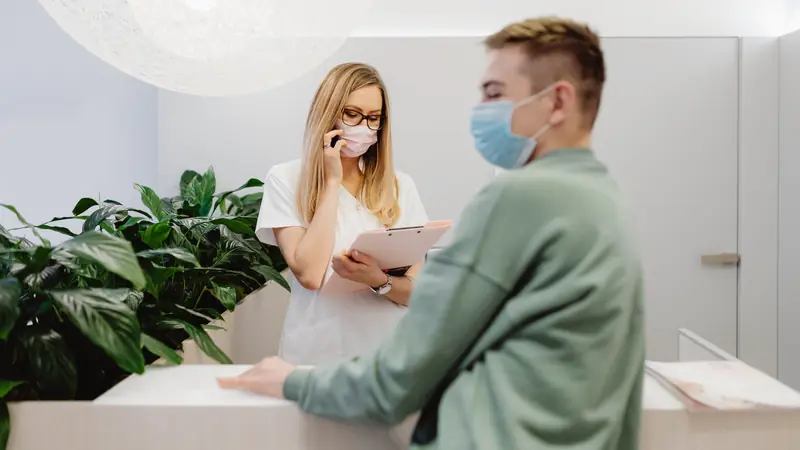 Patient échangeant avec une secrétaire à l'accueil d'un cabinet médical