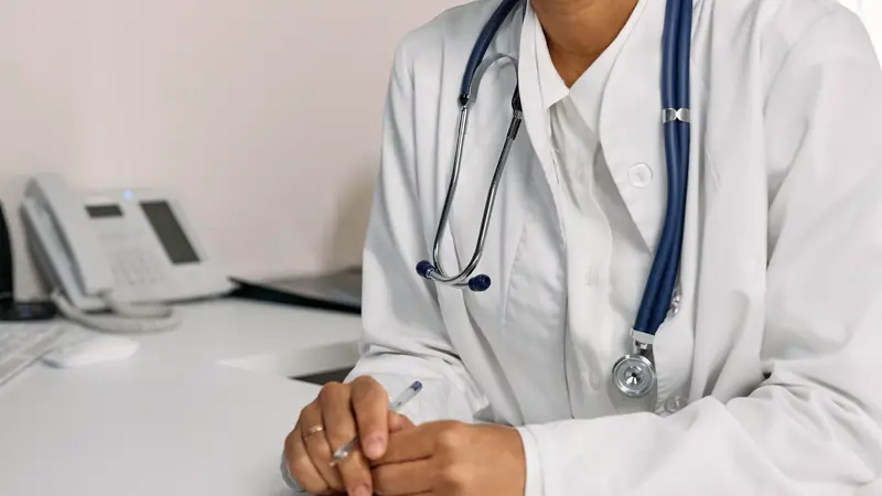 Médecin en blouse blanche remplissant un document à son bureau