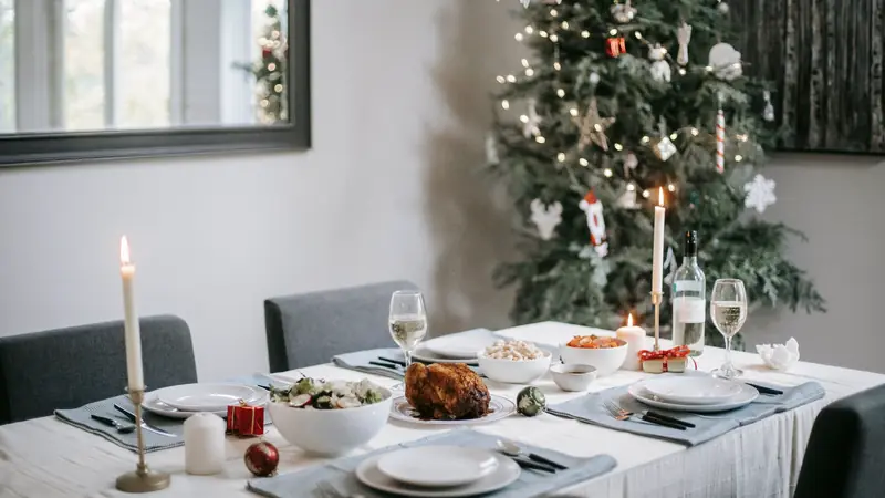 Table de Noël dressée avec une volaille rôtie, des bougies et des verres à vin