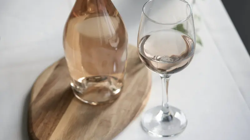 Carafe de vin rosé et verre posés sur une table blanche