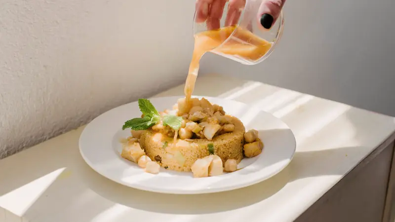Assiette de couscous que l'on arrose de bouillon