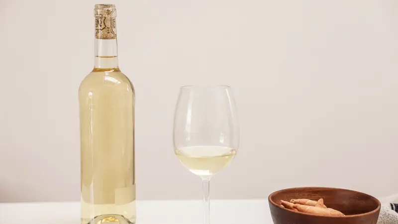 Bouteille et verre de vin blanc sur une table claire