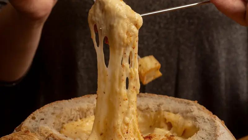 Fromage fondu qui file au bout d'une fourchette à fondue