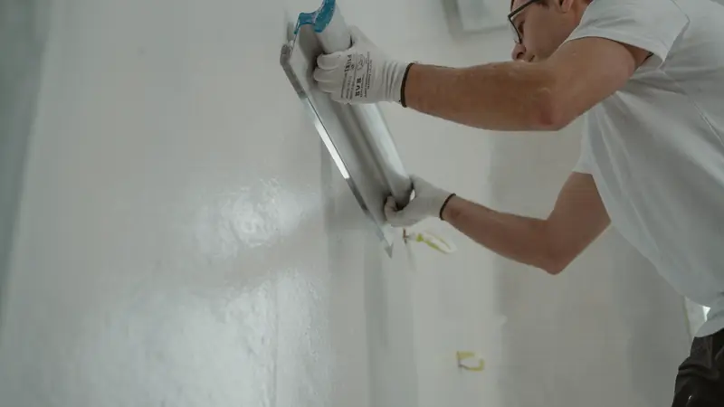 Artisan lissant un enduit sur un mur