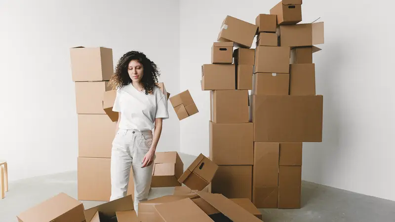 Femme entourée de cartons de déménagement dans une pièce claire
