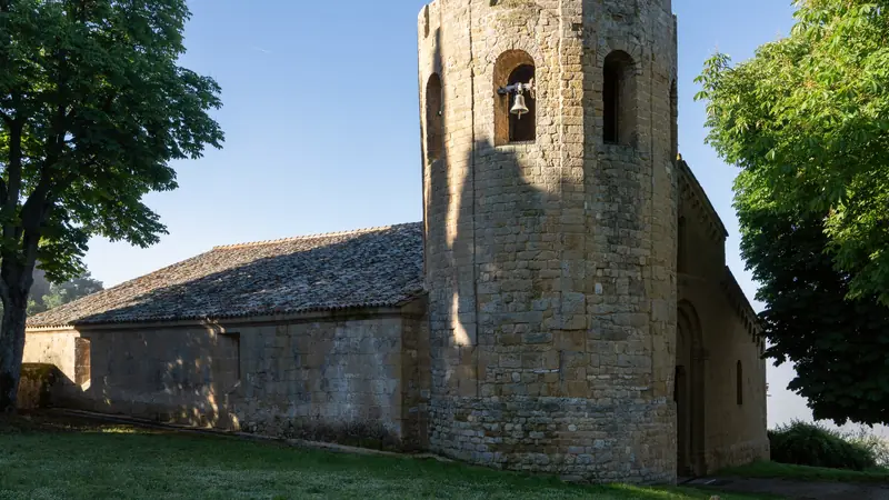 Église romane en pierre au clocher massif sous un ciel bleu